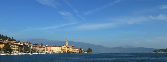 Ferienhaus beliebte Urlaubsziele am Gardasee -  Mit einer Fläche von 370 km² ist der Gardasee der größte See Italiens. Es liegt am Fuße der Alpen und erstreckt sich über drei Staaten: Lombardei, Venetien und Trentino. Die maximale Tiefe des Sees beträgt 346 m, er hat eine längliche Form und sein nördliches Ende ist sehr schmal. Dort ist der See von den Bergen der Gruppo di Baldo umgeben. Du trittst aus deinem gemütlichen Hotelzimmer und es begrüßt dich die warme italienische Sonne. Du blickst auf den atemberaubenden Gardasee, der in zahlreichen Blautönen schimmert - von tiefem Dunkelblau bis zu funkelndem Türkis. Majestätische Berge umgeben dich, während die Brise sanft deine Haut streichelt und der Duft von blühenden Zitronenbäumen deine Nase kitzelt. Du schlenderst die malerischen, engen Gassen entlang, vorbei an farbenfrohen, blumengeschmückten Häusern. Vereinzelt unterbricht das fröhliche Lachen der Einheimischen die friedvolle Stille. Du fühlst dich wie in einem Traum, der nicht enden will. Jeder Schritt führt dich zu neuen Entdeckungen und Abenteuern. Du probierst die köstliche italienische Küche mit ihren frischen Zutaten und verführerischen Aromen. Die Sonne geht langsam unter und taucht den Himmel in ein leuchtendes Orange-rot - ein spektakulärer Anblick.